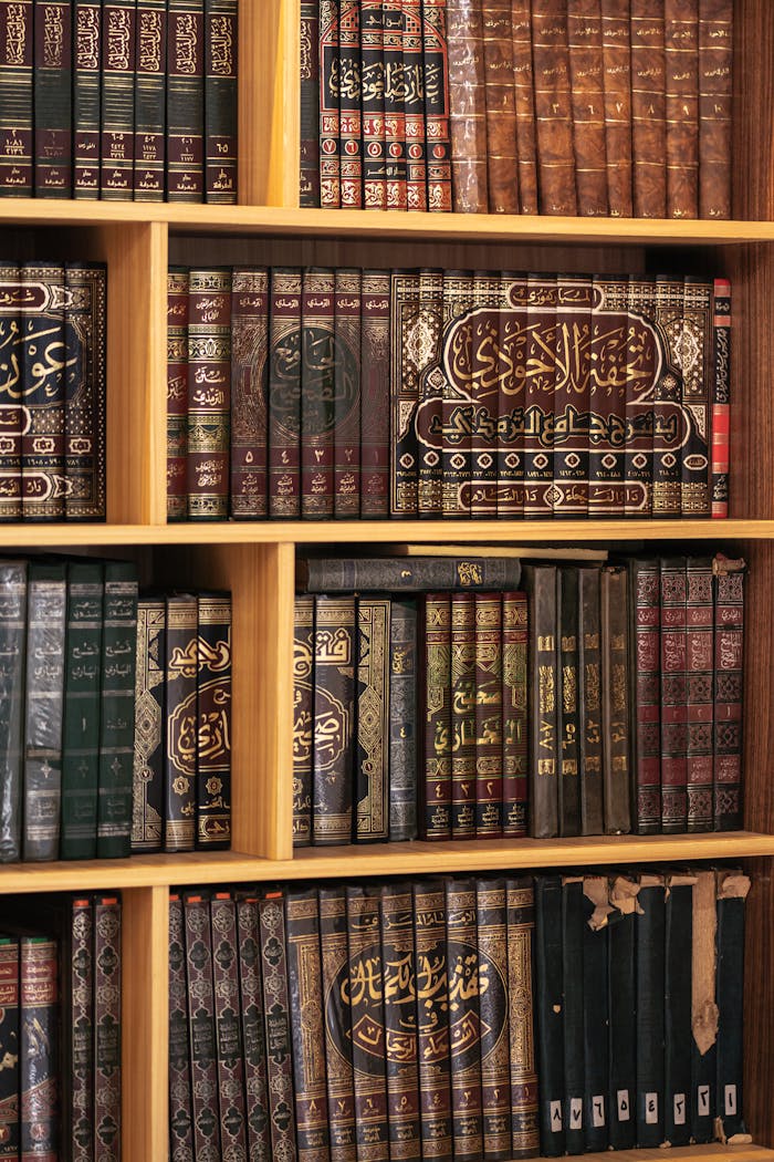 A detailed view of a bookshelf filled with ornate Islamic texts, showcasing intricate Arabic calligraphy.