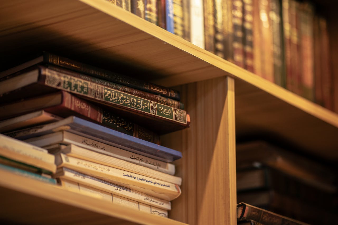 A stack of Islamic religious books on a wooden shelf, highlighting Arabic scripts and cultural significance.